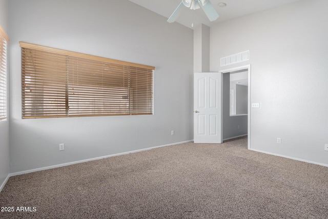 carpeted spare room featuring high vaulted ceiling, visible vents, ceiling fan, and baseboards