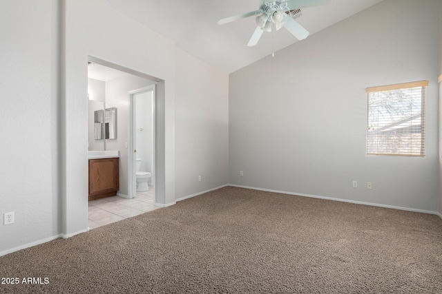 unfurnished bedroom featuring lofted ceiling, light tile patterned flooring, connected bathroom, light colored carpet, and baseboards