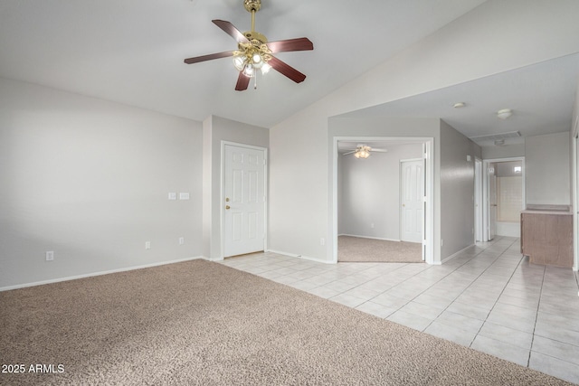 spare room with baseboards, light colored carpet, lofted ceiling, ceiling fan, and light tile patterned flooring