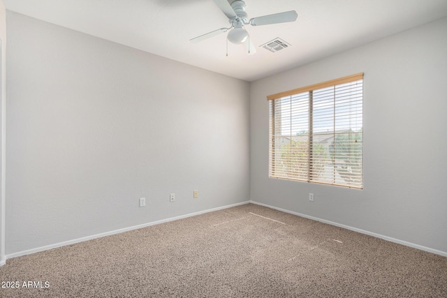 carpeted spare room featuring visible vents, ceiling fan, and baseboards