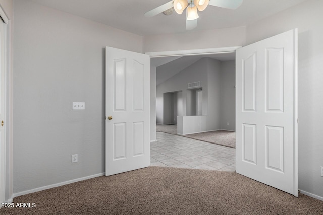 empty room featuring light tile patterned floors, light colored carpet, visible vents, a ceiling fan, and baseboards