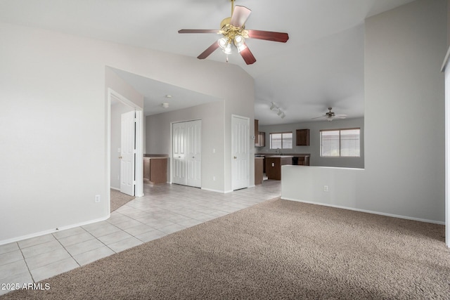 unfurnished living room with light carpet, light tile patterned floors, a ceiling fan, vaulted ceiling, and a sink