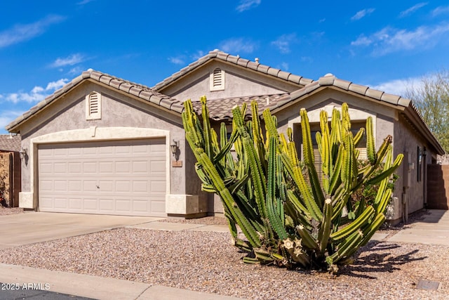 view of front facade featuring an attached garage, driveway, a tile roof, and stucco siding