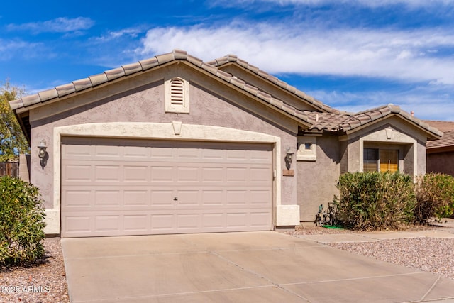 ranch-style house with a garage, concrete driveway, a tile roof, and stucco siding