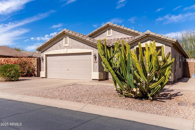 view of front of property featuring driveway, an attached garage, a tile roof, and stucco siding