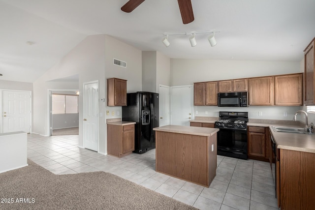 kitchen featuring black appliances, light countertops, a sink, and a center island