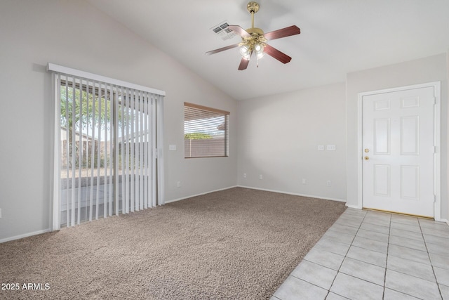 empty room with light tile patterned floors, visible vents, light carpet, vaulted ceiling, and ceiling fan