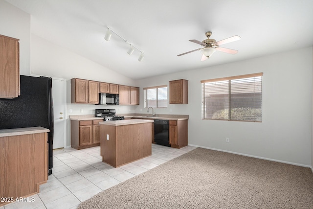 kitchen with a center island, lofted ceiling, light countertops, a sink, and black appliances