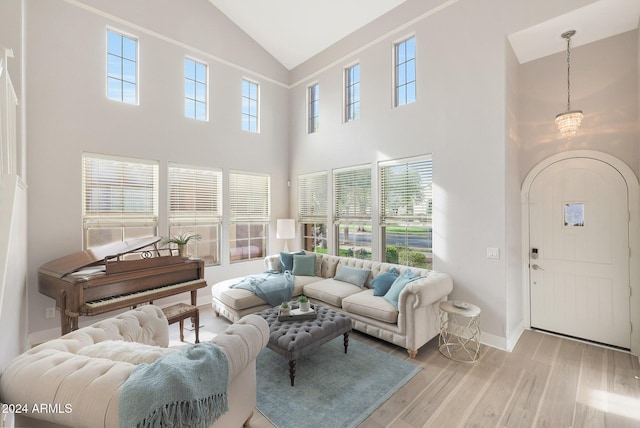 living room with an inviting chandelier, high vaulted ceiling, and light hardwood / wood-style flooring