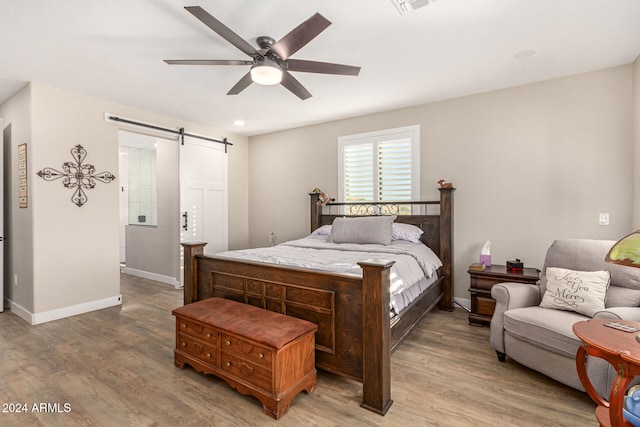 bedroom featuring ceiling fan, hardwood / wood-style flooring, and a barn door