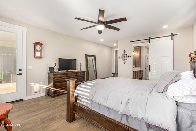 bedroom with ensuite bathroom, hardwood / wood-style floors, a barn door, and ceiling fan