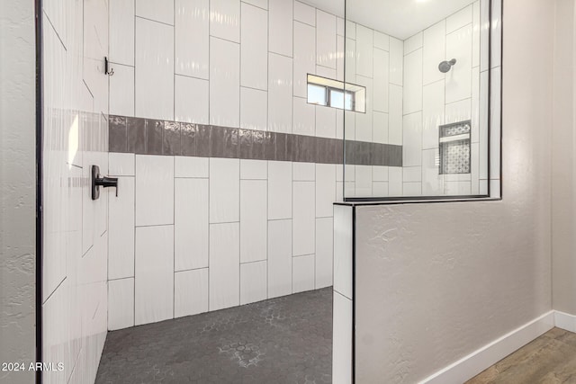 bathroom with a tile shower and hardwood / wood-style flooring