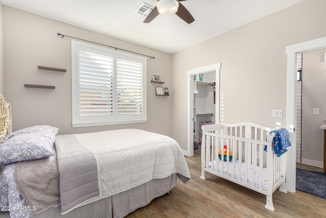 bedroom with hardwood / wood-style floors, a walk in closet, a closet, and ceiling fan