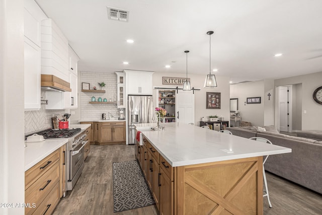 kitchen featuring a spacious island, dark hardwood / wood-style floors, a kitchen breakfast bar, stainless steel range, and white cabinetry