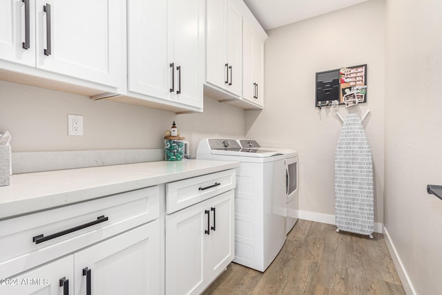 washroom with independent washer and dryer, light wood-type flooring, and cabinets