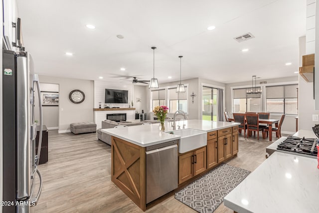 kitchen featuring hanging light fixtures, appliances with stainless steel finishes, sink, and a kitchen island with sink