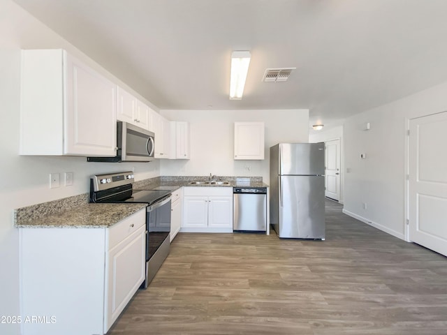 kitchen with visible vents, white cabinetry, a sink, light wood finished floors, and appliances with stainless steel finishes