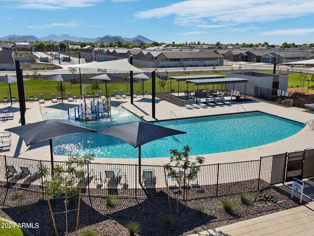 pool with a patio area, fence, a mountain view, and a residential view