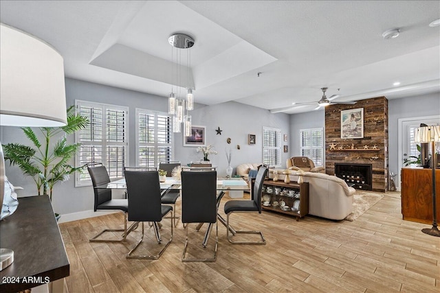 dining area with light hardwood / wood-style flooring, a healthy amount of sunlight, ceiling fan with notable chandelier, and a fireplace