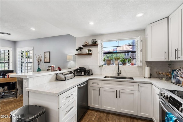 kitchen featuring plenty of natural light, dark wood finished floors, appliances with stainless steel finishes, a peninsula, and a sink