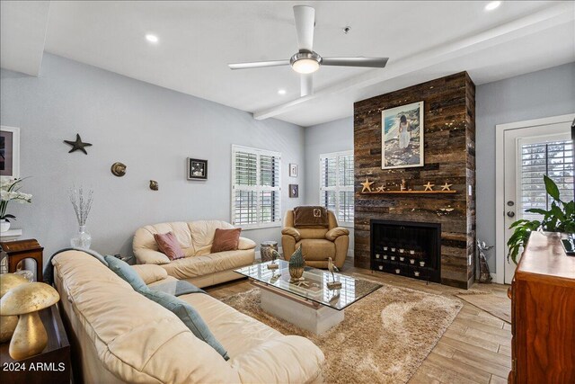 living room featuring a fireplace, ceiling fan, and light hardwood / wood-style floors