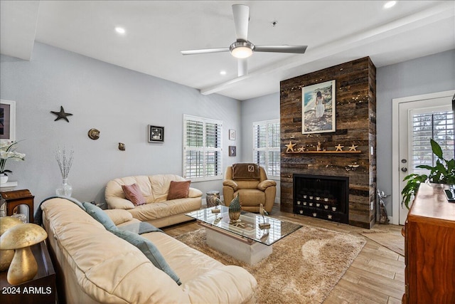 living area with a large fireplace, plenty of natural light, wood finished floors, and a ceiling fan