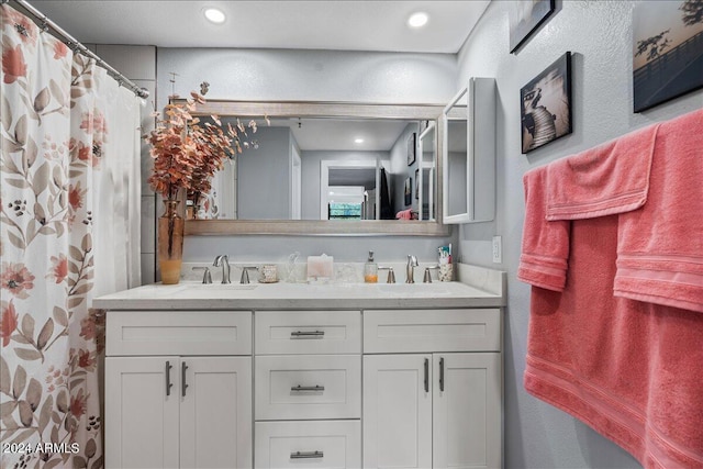 full bath featuring double vanity, a sink, and recessed lighting