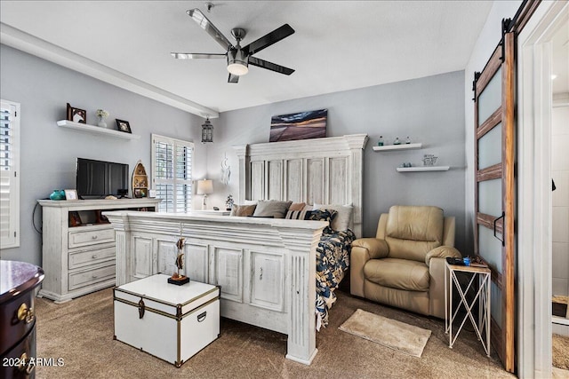 carpeted bedroom with ceiling fan and a barn door