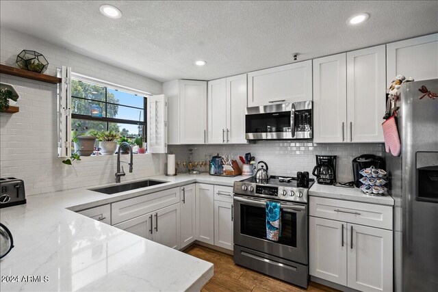 kitchen with backsplash, sink, appliances with stainless steel finishes, and white cabinetry