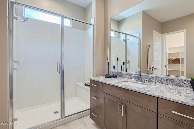 full bathroom with a stall shower, vanity, tile patterned floors, and a walk in closet