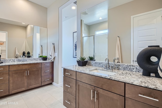 full bath with a shower stall, tile patterned floors, two vanities, and baseboards