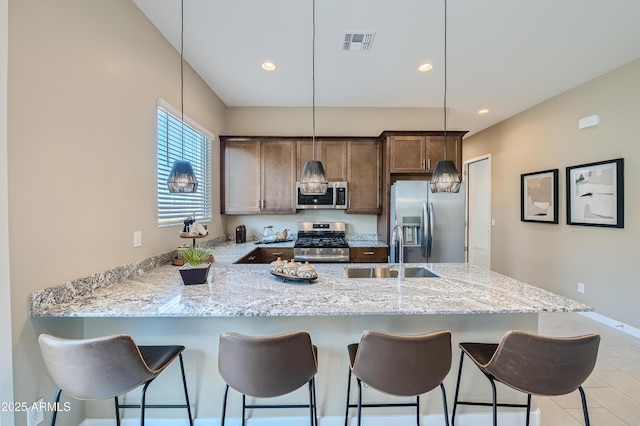 kitchen with stainless steel appliances, a sink, light stone countertops, a peninsula, and recessed lighting