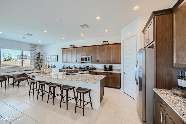 kitchen featuring stainless steel appliances, a sink, a breakfast bar, recessed lighting, and light tile patterned floors