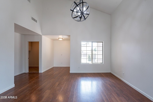 unfurnished living room featuring a chandelier, dark wood-type flooring, and high vaulted ceiling