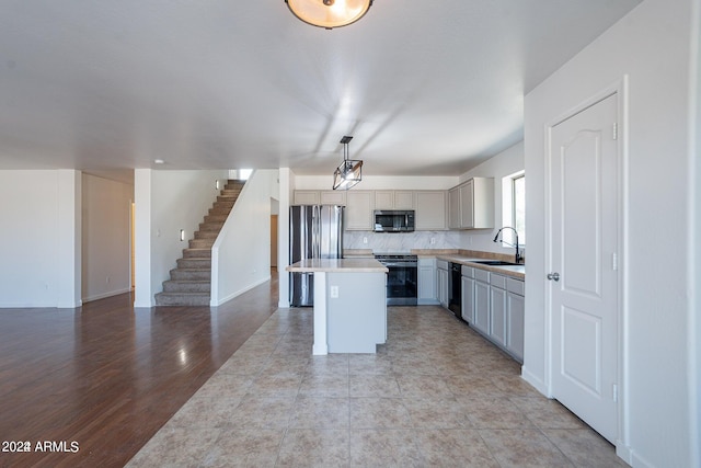 kitchen featuring light hardwood / wood-style floors, gray cabinetry, pendant lighting, a kitchen island, and stainless steel appliances