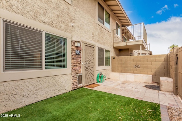 entrance to property with a patio area, fence, and stucco siding