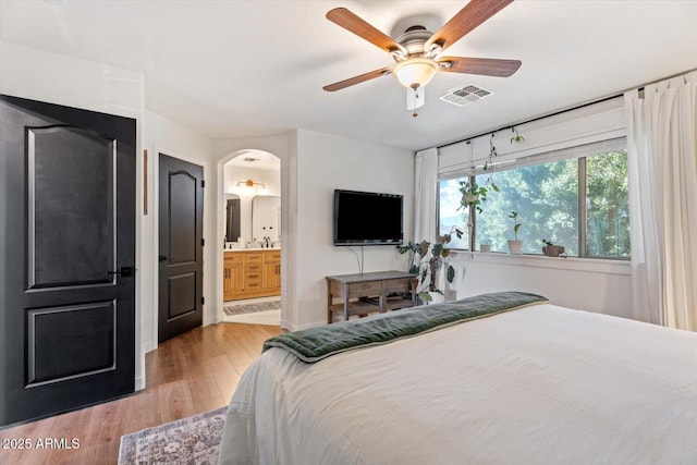 bedroom featuring ceiling fan, ensuite bathroom, and light wood-type flooring