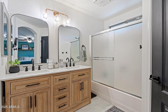 bathroom featuring ceiling fan, enclosed tub / shower combo, and vanity