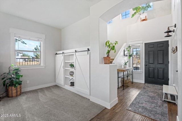 foyer entrance with a barn door and dark hardwood / wood-style flooring