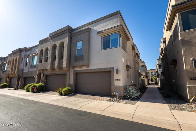 townhome / multi-family property featuring stucco siding, a residential view, and a garage
