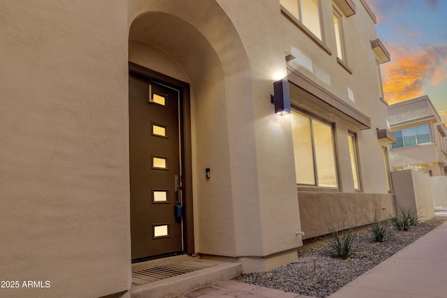 exterior entry at dusk featuring stucco siding