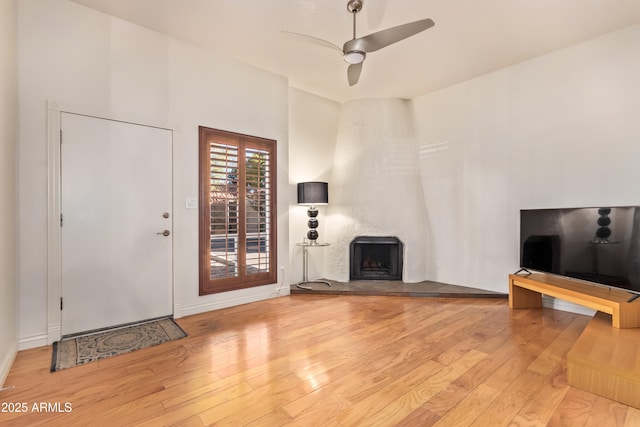 unfurnished living room with hardwood / wood-style flooring, a large fireplace, and ceiling fan