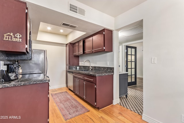 kitchen featuring sink, stainless steel dishwasher, light hardwood / wood-style flooring, and a raised ceiling