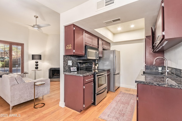 kitchen featuring light hardwood / wood-style floors, appliances with stainless steel finishes, sink, backsplash, and ceiling fan