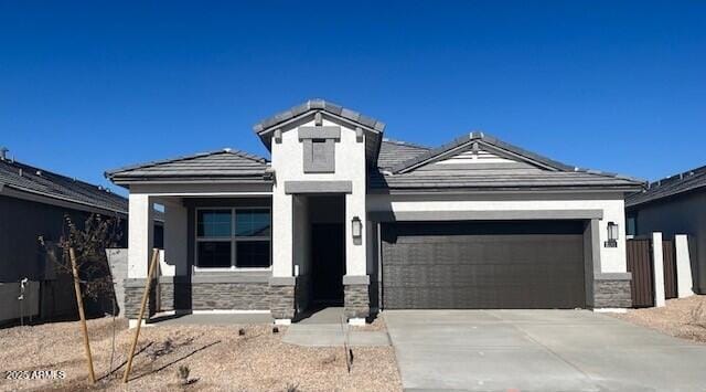 25467 W Graham Trl, Buckeye, AZ 85326 - view of front facade featuring a garage, stucco siding, stone siding, and driveway