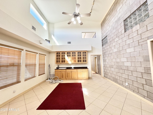 kitchen featuring dark countertops, visible vents, glass insert cabinets, rail lighting, and light tile patterned flooring