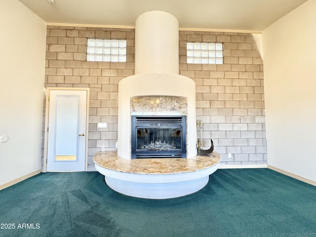 unfurnished living room with baseboards, carpet, and a glass covered fireplace