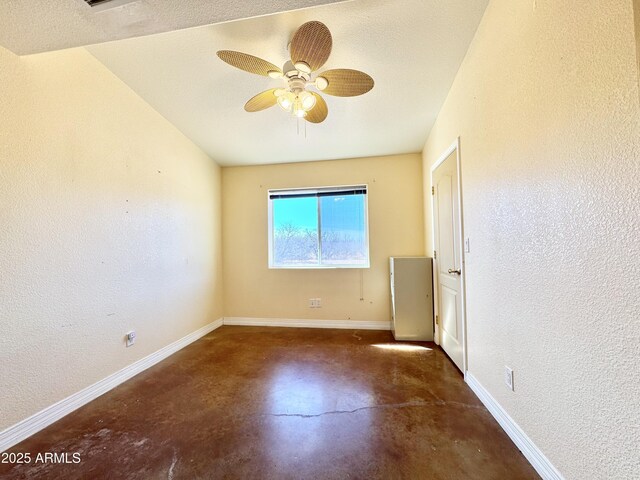 spare room featuring concrete flooring, baseboards, and a textured wall