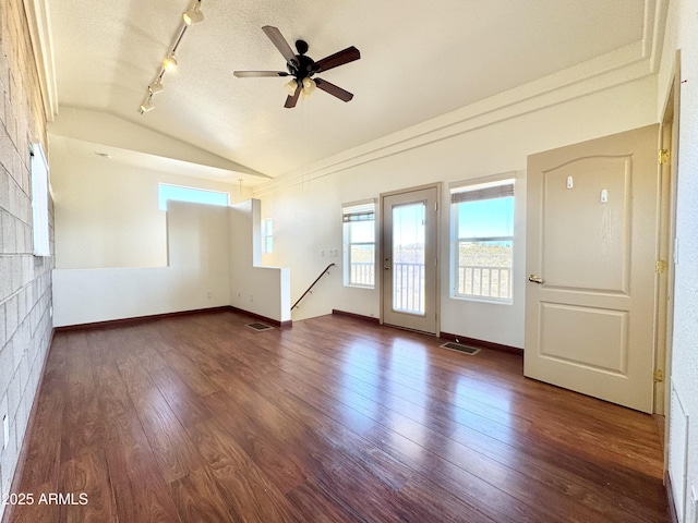 empty room featuring visible vents, baseboards, lofted ceiling, and wood finished floors