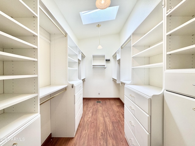 spacious closet featuring a skylight and wood finished floors